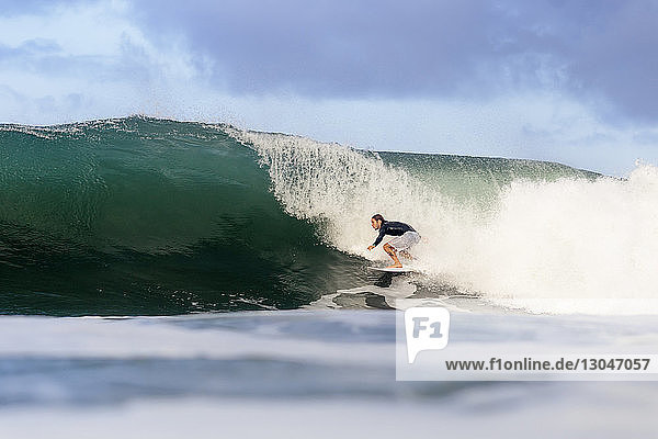 Carefree man surfing on sea against sky