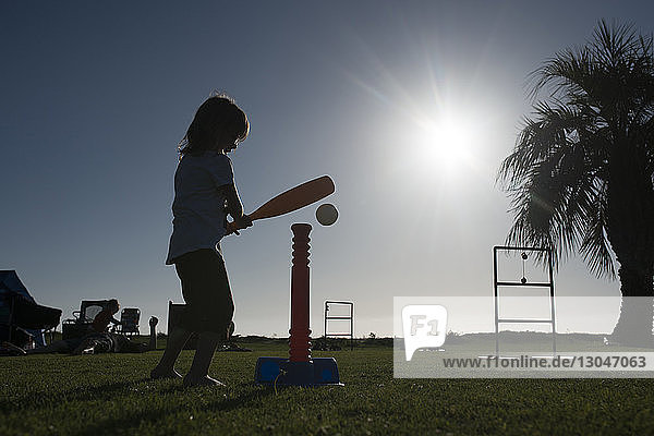 Seitenansicht eines Mädchens  das im Sommer im Park mit T-Ball spielt