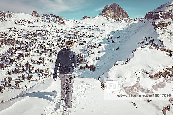 Rear view of woman walking on snowy field at Grand Teton National Park