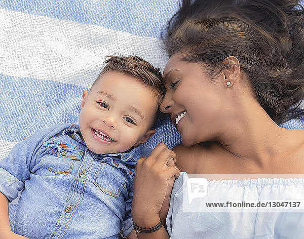 Kopfporträt eines Sohnes  der mit der Mutter auf einer Decke liegt
