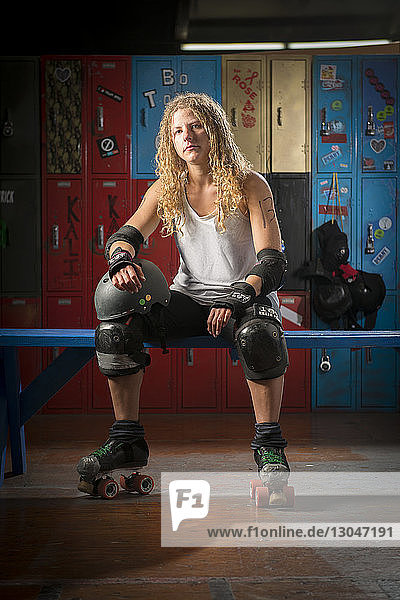 Portrait of confident woman wearing roller skates while sitting on table in locker room