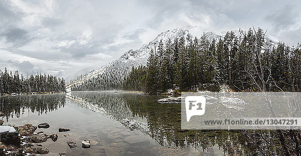 Scenic view of String Lake by trees against cloudy sky at Grand Teton National Park during winter