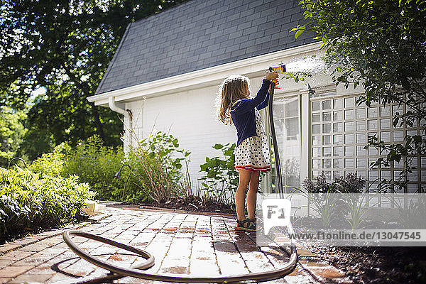 Girl watering plants in backyard