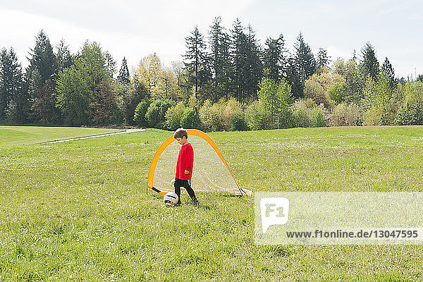 Boy playing soccer on grassy field during sunny day