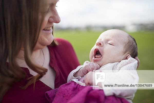 Close-up of smiling mother looking at daughter with mouth open in park
