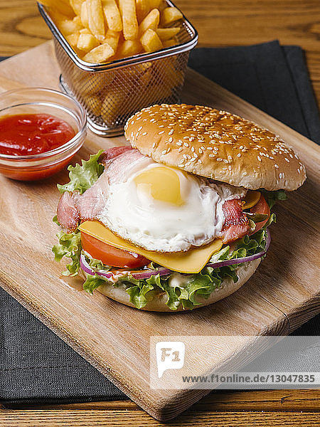 Nahaufnahme von Burger mit Pommes Frites und Ketchup auf Holzschneidebrett serviert