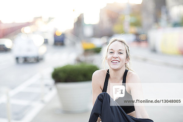 Porträt einer lächelnden Sportlerin  die auf einem Fußweg in der Stadt steht