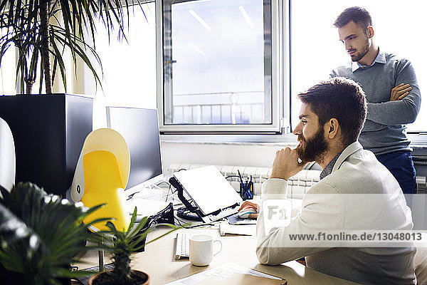 Businessmen using desktop computer in creative office