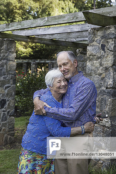Portrait of senior couple embracing while standing in park