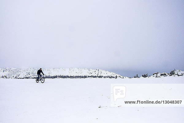 Mann fährt Fahrrad auf schneebedecktem Feld