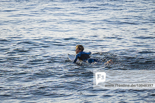 Junger Mann schaut beim Surfen auf See weg