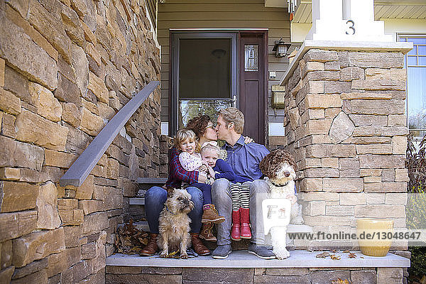 Porträt von Schwestern mit küssenden Eltern und Hunden auf Stufen gegen das Haus