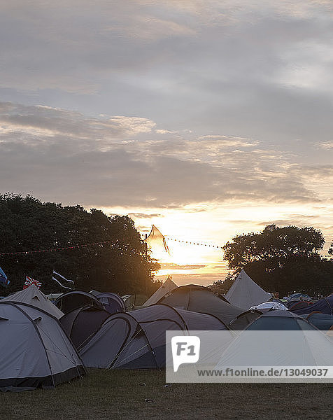 Zelte gegen bewölkten Himmel auf dem Campingplatz bei Sonnenuntergang