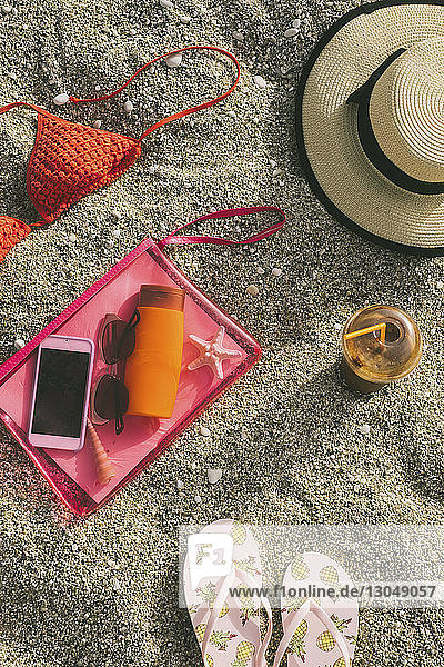 Hochwinkelansicht von Strandvorräten mit Smartphone auf Sand
