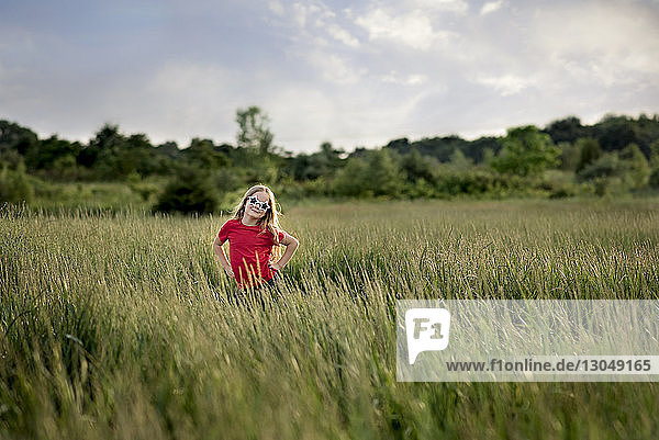Portrait of confident girl wearing star shape sunglasses while standing amidst field