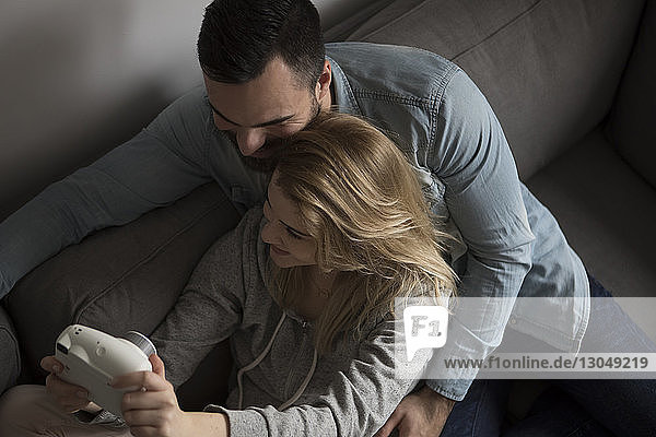 Schrägaufnahme eines glücklichen Paares  das sich beim Sitzen auf dem Sofa zu Hause selbstständig macht