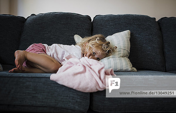 Portrait of girl lying on sofa at home