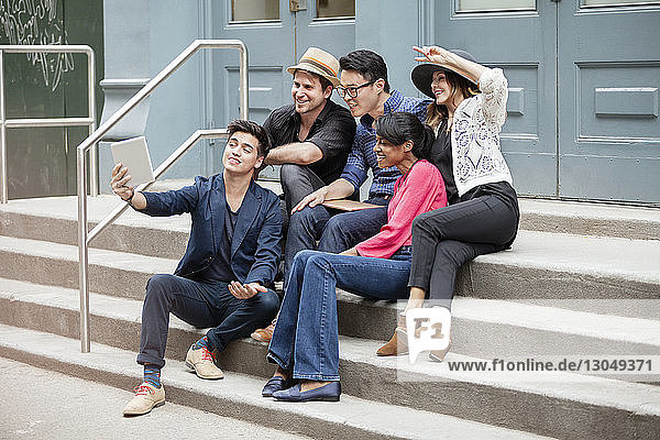 Creative business people taking selfie while sitting on steps