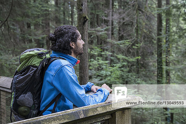 Wanderer mit Rucksack schaut weg  während er am Beobachtungspunkt im Wald steht