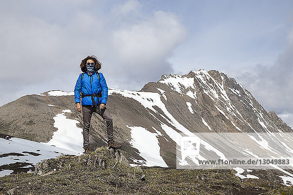 Selbstbewusster Wanderer in voller Länge mit schalbedecktem Mund gegen Berge
