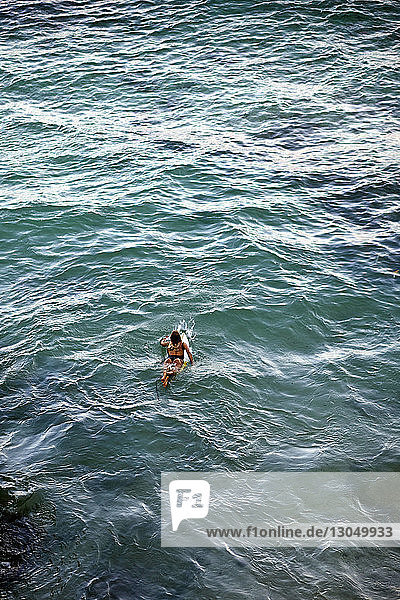 Hochwinkelaufnahme einer Frau beim Surfen im Meer