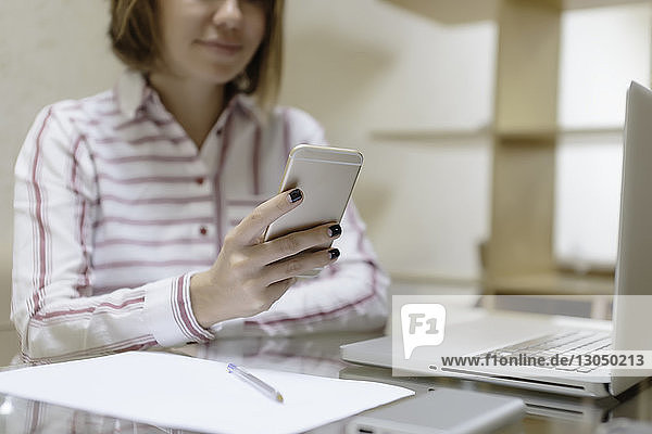 Ein Teil der Geschäftsfrau benutzt ein Smartphone bei der Arbeit im Heimbüro