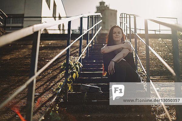 Porträt einer selbstbewussten Frau mit Geldbörse  die an einem sonnigen Tag auf einer Treppe sitzt