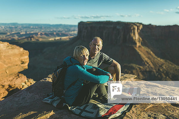 Porträt eines Wanderpaares  das auf einem Berg vor einer Felsformation im Canyonlands-Nationalpark sitzt