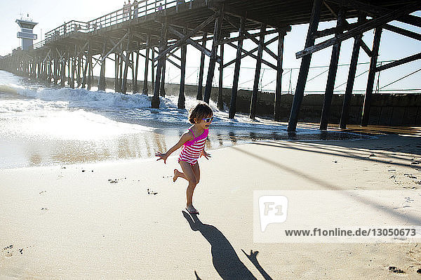 Full length of girl running on shore at Seal Beach