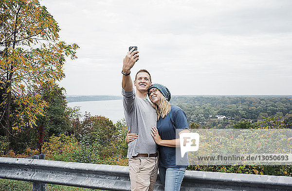 Happy couple taking selfie against sky