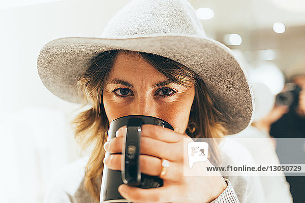 Porträt einer Geschäftsfrau mit Hut beim Kaffeetrinken im Hotel