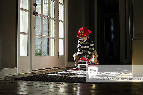 Playful boy driving toy fire engine at home