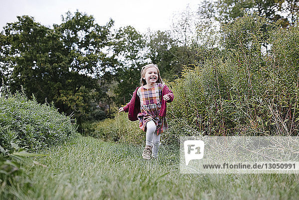 Fröhliches Mädchen läuft in voller Länge auf dem Spielfeld im Park