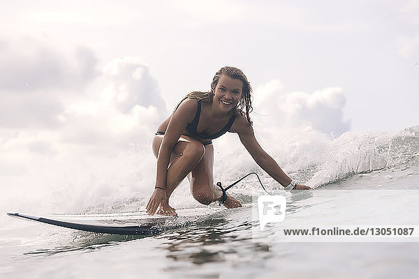 Portrait of carefree smiling woman surfing in sea