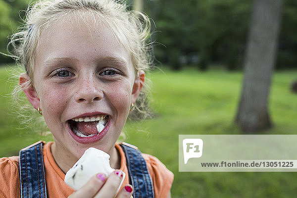 Porträt eines glücklichen Mädchens beim Marshmallow-Essen auf dem Feld