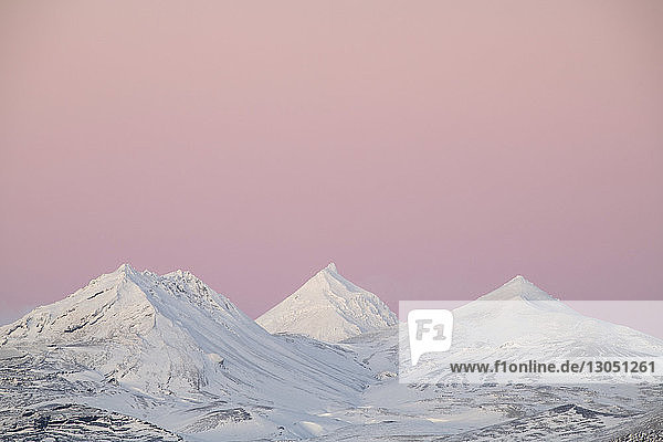 Idyllischer Blick auf schneebedeckte Berge vor dramatischem Himmel