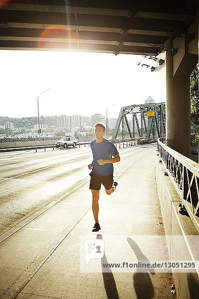 Sportlicher Mann joggt auf einer Brücke in der Stadt