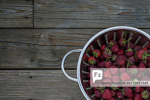 Hochwinkelansicht von Erdbeeren im Sieb auf Holztisch