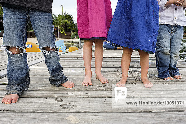 Low section of friends standing on wooden jetty at park