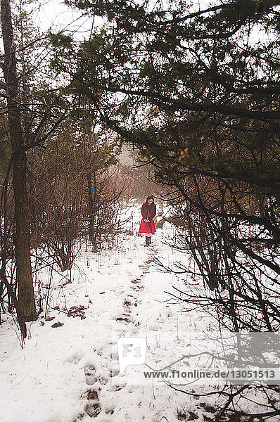 Girl walking on snowy field amidst forest