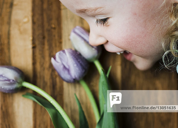Hochwinkelansicht eines lächelnden Mädchens bei lila Tulpen auf dem Tisch