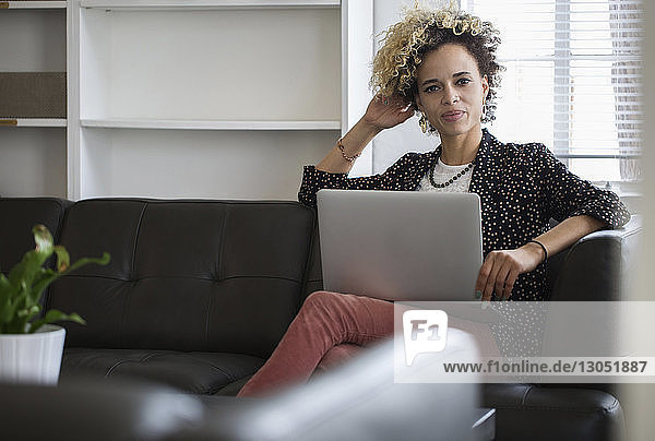 Porträt einer selbstbewussten Geschäftsfrau mit Laptop-Computer  die im Büro auf dem Sofa sitzt