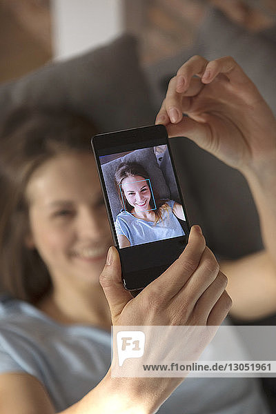 Hochwinkelansicht einer Frau  die zu Hause auf einem Smartphone auf sich selbst klickt
