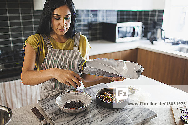 Frau entfernt Schokoladenstückchen in Schüssel  während sie an der Küchentheke steht