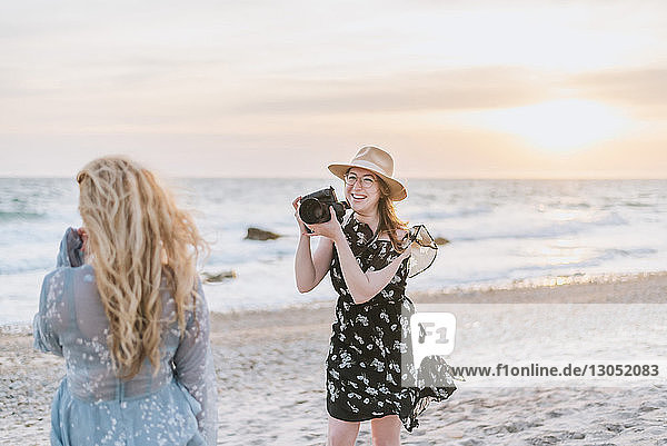 Junge Frau fotografiert Freundin am windigen Strand, Menemsha, Martha's Vineyard, Massachusetts, USA