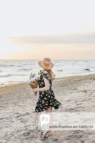 Junge Frau mit Blumenstrauss am windigen Strand, Menemsha, Martha's Vineyard, Massachusetts, USA
