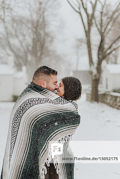 In eine Decke gehülltes Paar küsst sich in verschneiter Landschaft  Georgetown  Kanada