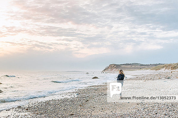 Junge Frau schaut vom windigen Strand aufs Meer hinaus  Menemsha  Martha's Vineyard  Massachusetts  USA