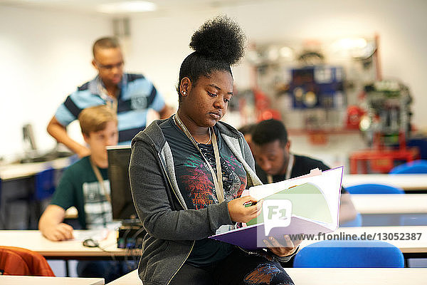 Female higher education student reading file in college classroom