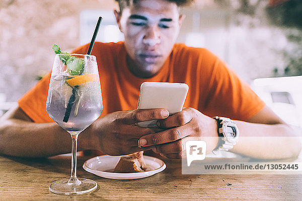Mann schreibt SMS und trinkt in Bar